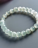 Load image into Gallery viewer, Beaded bracelet with light green beads on a gray background