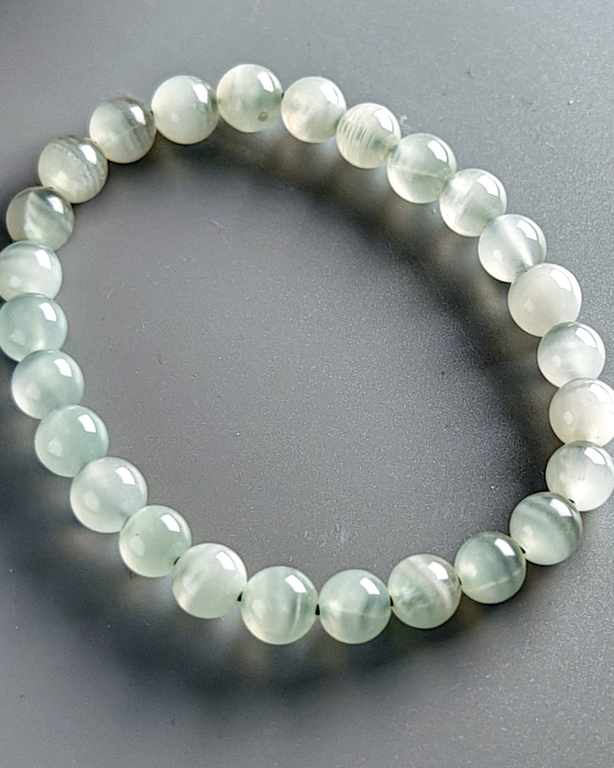 Beaded bracelet with light green beads on a gray background