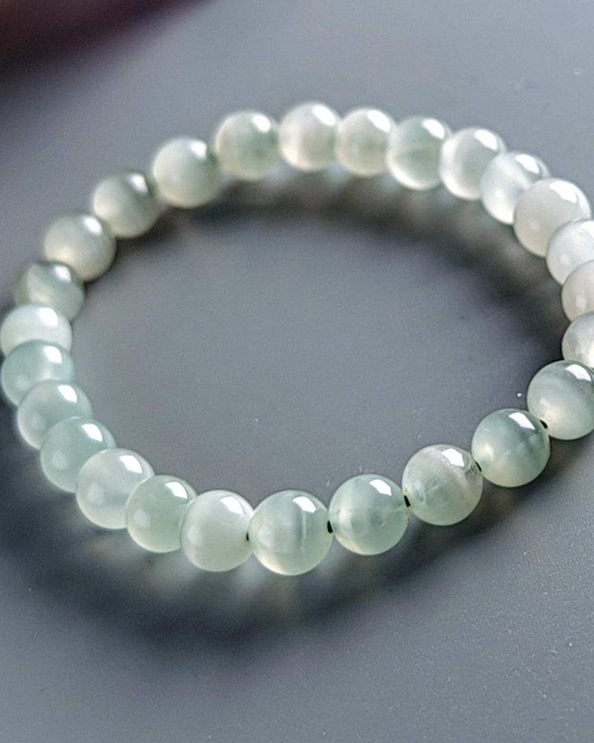 Beaded bracelet with light green beads on a gray background